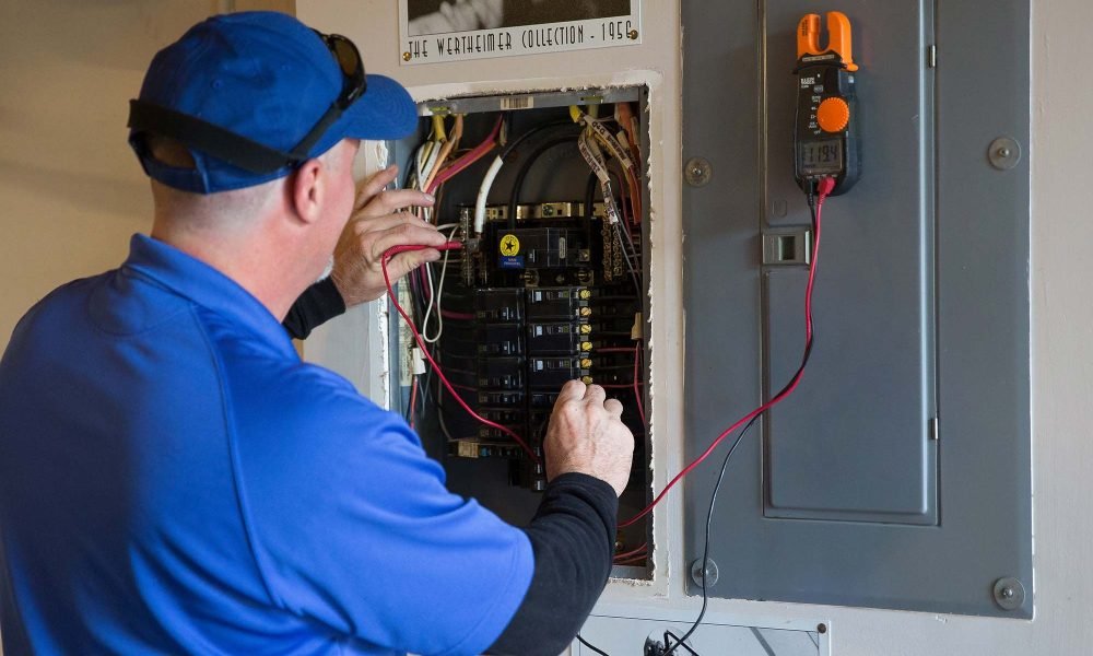 Electrician metering a breaker panel with a clamp meter during a troubleshooting call